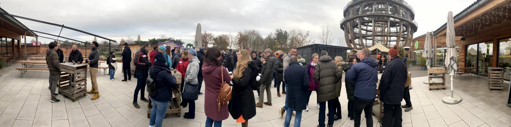 Eine Gruppe von Mitarbeitenden vor einer großen begehbaren Holzkugel